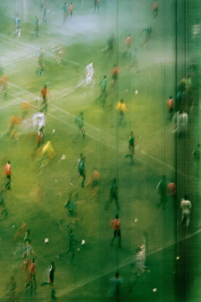 abstract football broadcast image of players on a green pitch, Egypt national team match, tiny figures scattered across the field, extreme motion smear, vertical distortion, photographed off a television screen, visible pixel grid, scanlines, analog noise, soft blur, raw experimental sports aesthetic